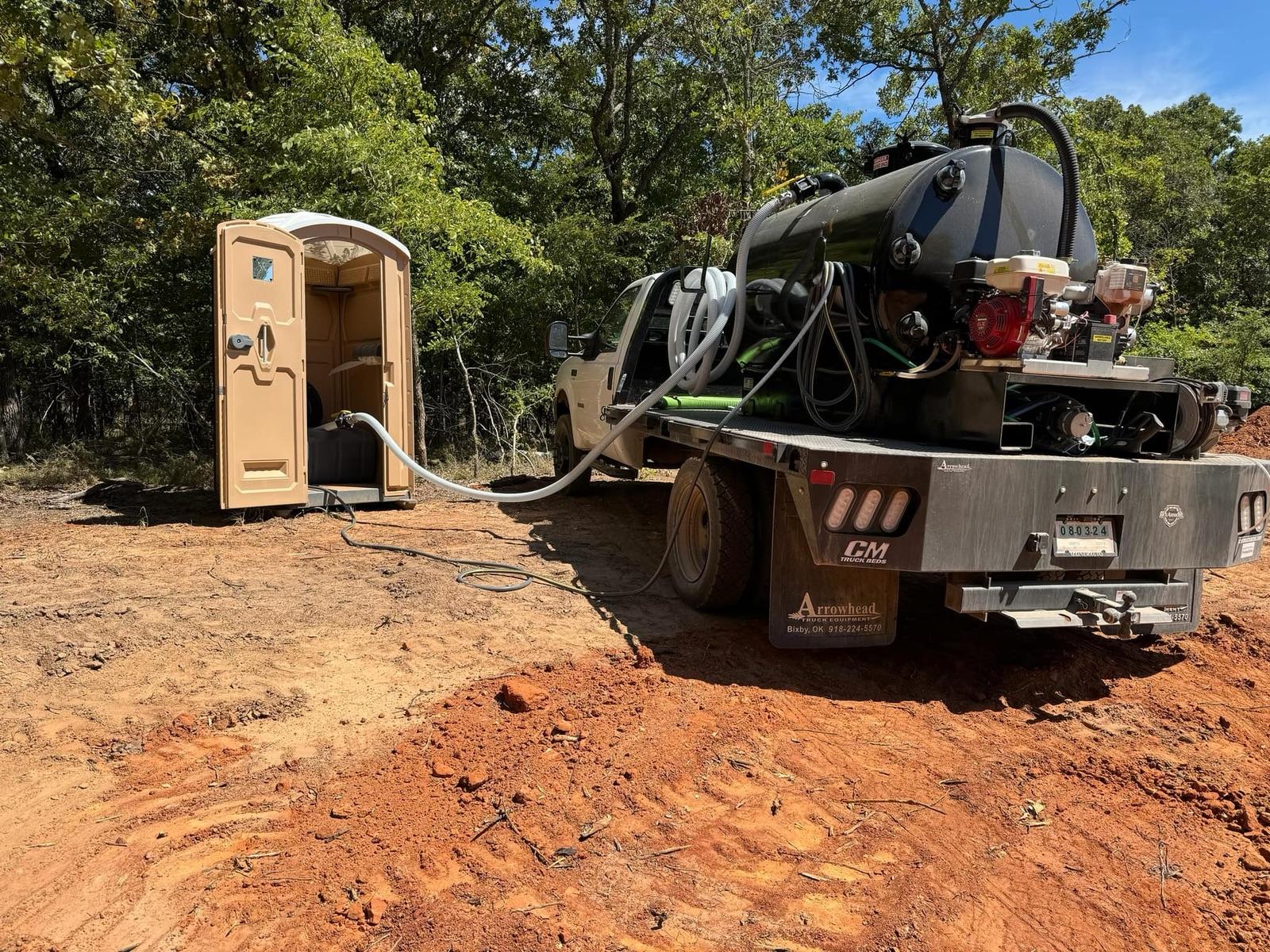 K&M service truck cleaning a porta potty on a job site